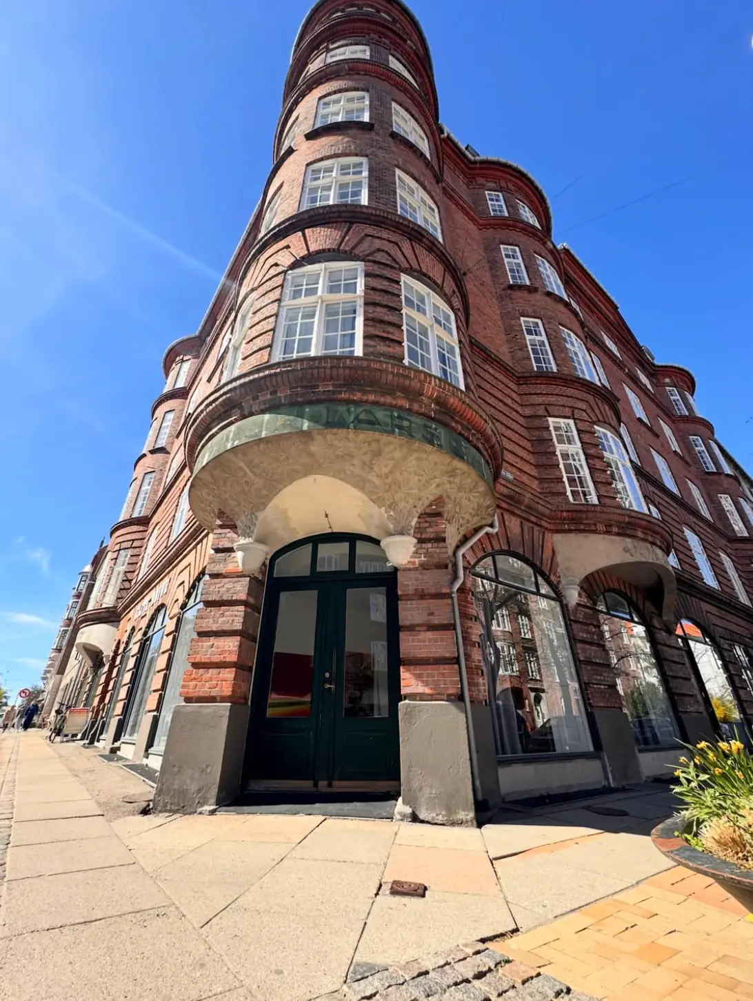 Rødt teglhjørne med karnapper på Vesterbrogade 198, Frederiksberg, set nedefra mod en blå himmel